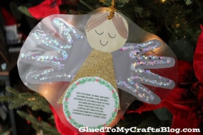 A handmade handprint angel ornament with glittery wings and a heartfelt poem, hanging on a Christmas tree.