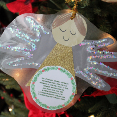 A handmade handprint angel ornament with glittery wings and a heartfelt poem, hanging on a Christmas tree. The image features text: “GluedToMyCraftsBlog.com” at the top and “FREE PRINTABLE!!!” at the bottom in red.
