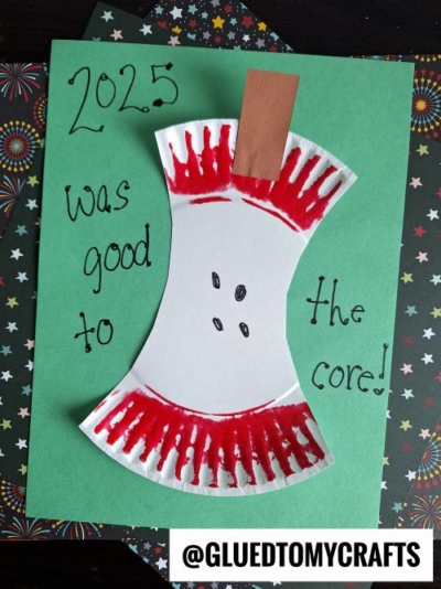 A fun New Year’s Eve Crafts For Kids project shows a paper plate cut and colored as an eaten apple core, glued to green paper. The text reads 2025 was good to the core! with the @GLUEDTOMYCRAFTS watermark at the bottom.
