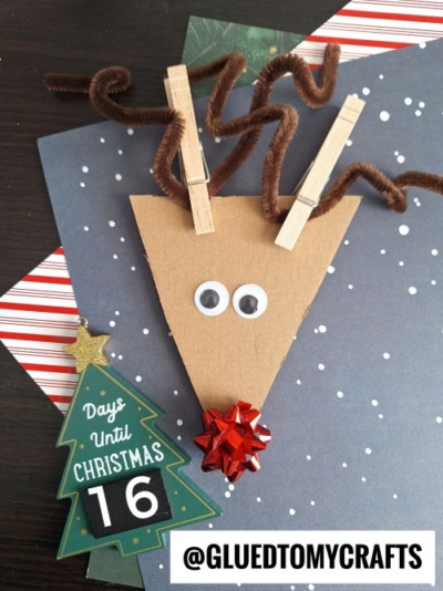 A fun reindeer craft for CHRISTMAS CRAFTS FOR KIDS, made with brown paper, googly eyes, a red bow nose, clothespins and pipe cleaners for antlers. A countdown calendar shows 16 days left. Snow and stripes decorate the festive background.