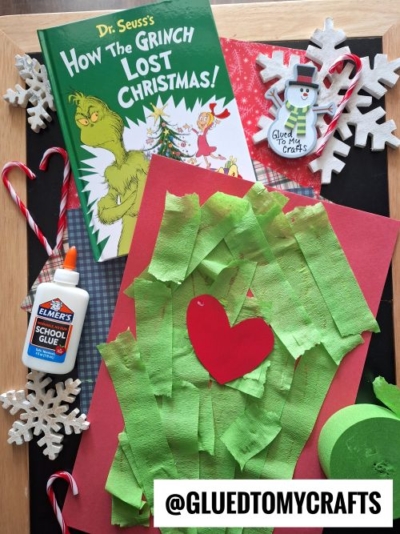 A flat lay features the book How the Grinch Lost Christmas! by Dr. Seuss, CHRISTMAS CRAFTS FOR KIDS like a Grinch-themed green tissue paper craft with a red heart, glue, candy canes, felt snowflakes, and a snowman ornament. @GluedToMyCrafts text is shown.