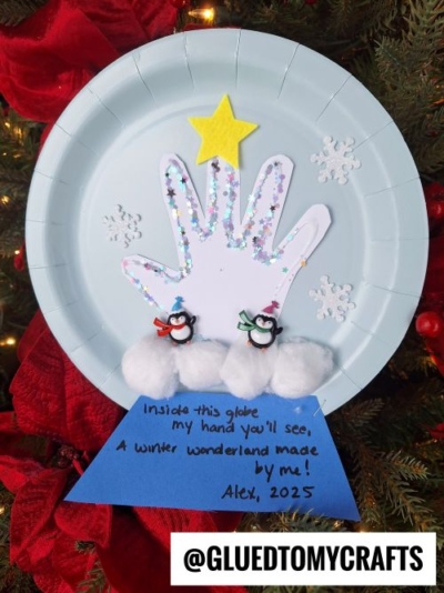 A festive paper plate CHRISTMAS CRAFTS FOR KIDS idea: a white handprint with glitter, a yellow star, snowflakes, two penguins on cotton balls, and a blue note saying A winter wonderland made by me! Alex, 2025.