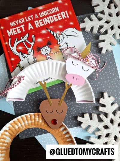 A children’s book titled “Never Let a Unicorn Meet a Reindeer!” is surrounded by CHRISTMAS CRAFTS FOR KIDS, including unicorn and reindeer paper plate crafts, large decorative snowflakes, and a @GLUEDTOMYCRAFTS label.
