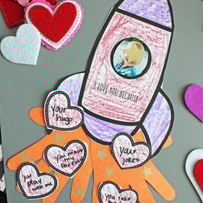 A colorful rocket craft made with hearts and felt, featuring a child's photo in the center.