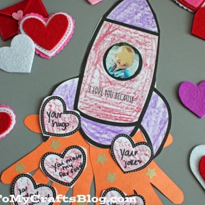 A handmade card with a rocket drawing, hearts, and messages of love. Felt hearts and an envelope are around it.