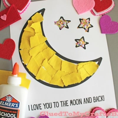 A colorful craft project featuring a yellow felt moon, sparkly stars, and heart shapes, with glue and a heartfelt message.
