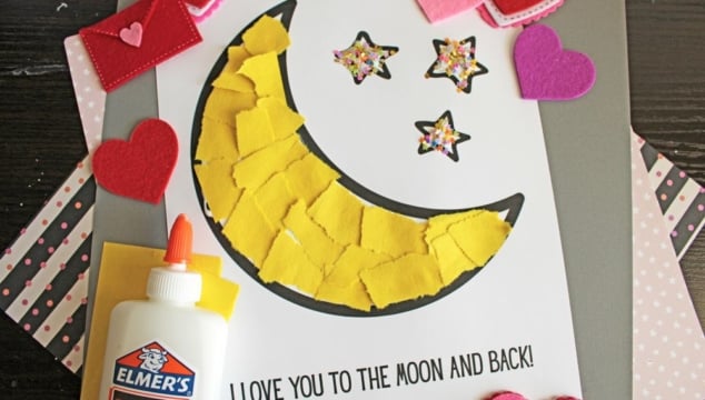 A colorful craft project featuring a yellow felt moon, sparkly stars, and heart shapes, with glue and a heartfelt message.