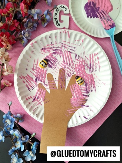 A paper plate with a hand and a paintbrush on it.