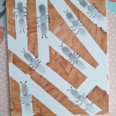 A canvas with brown and white geometric shapes and black fingerprint ants, with six legs and antennae drawn in black, on top. The image has a watermark that says @GLUEDTOMYCRAFTS.