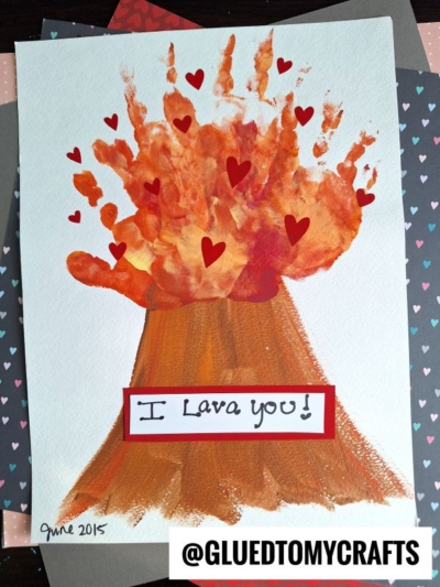 Children’s craft of a volcano erupting, made with painted handprints as lava and hearts scattered around. Text says I Lava you! in a box at the bottom, with @GLUEDTOMYCRAFTS watermark and “June 2015” signature.