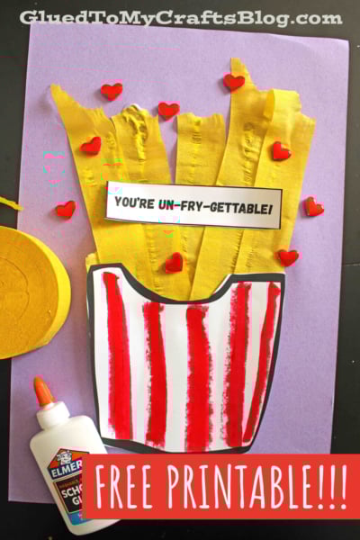 A craft project of French fries made from yellow crepe paper and red heart embellishments in a red-striped container, with a sign reading YOURE UN-FRY-GETTABLE! and a bottle of glue. Text says FREE PRINTABLE!!!.