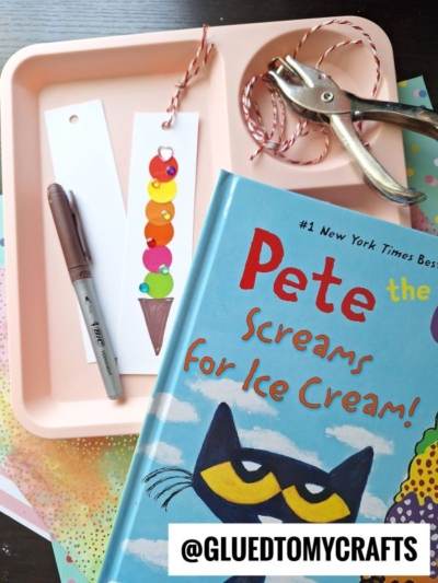 A tray holds a brown pen, a bookmark decorated with colorful paper circles as ice cream scoops, red and white twine, and a hole punch. In front is the book Pete the Cat: Screams for Ice Cream.