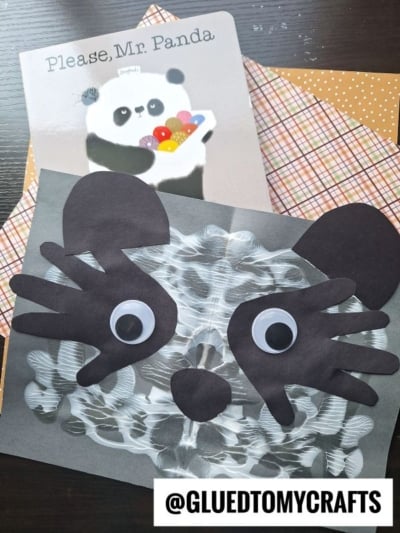 A children’s book titled Please, Mr. Panda sits above a panda craft made of black paper shapes and googly eyes on a painted white and black background, with patterned paper underneath.