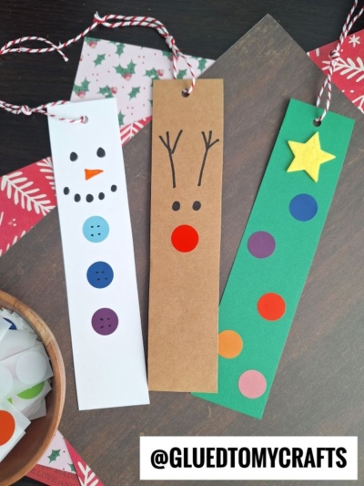 Three handmade bookmarks: a snowman with a carrot nose and button details, a reindeer with antlers and red nose, and a green bookmark with colorful dots and a yellow star—perfect coding label crafts, each finished with tied string loops.