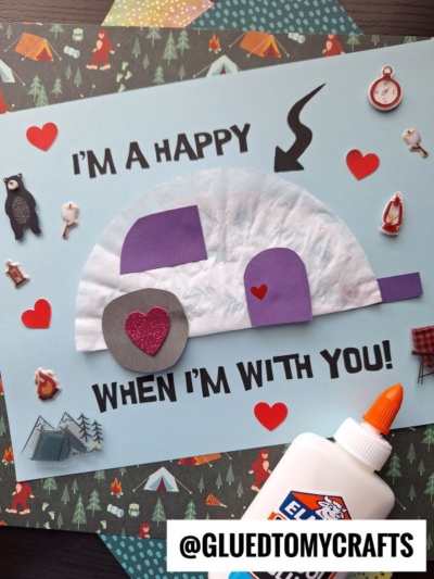 A handmade card features a purple and white camper made from paper shapes, heart stickers, and the words IM A HAPPY CAMPER WHEN IM WITH YOU! surrounded by camping-themed stickers—perfect inspiration for coffee filter crafts for kids.