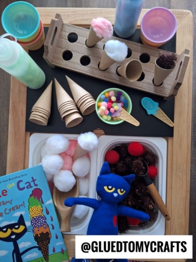 A Pete the Cat plush sits by craft supplies for pretend ice cream: felt cones, pom-poms, paper cones, bottles, and a book titled Pete the Cat: I Scream for Ice Cream. @GLUEDTOMYCRAFTS is labeled on the image.