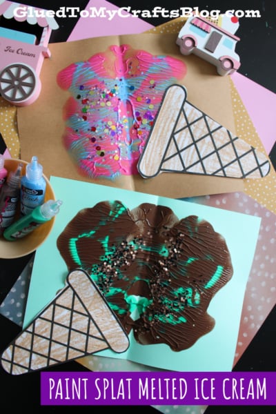 Two colorful paint splat artworks shaped like melted ice cream, each with a paper cone, are displayed on colored paper. Craft supplies and ice cream-themed decorations are arranged around them.