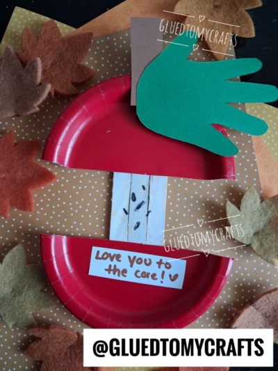 A red paper plate apple core craft with a green handprint leaf, felt leaves, and a note saying Love you to the core! displayed on a polka-dot background. This adorable mother’s day apple core craft is perfect for little hands. @GluedToMyCrafts text is overlaid.