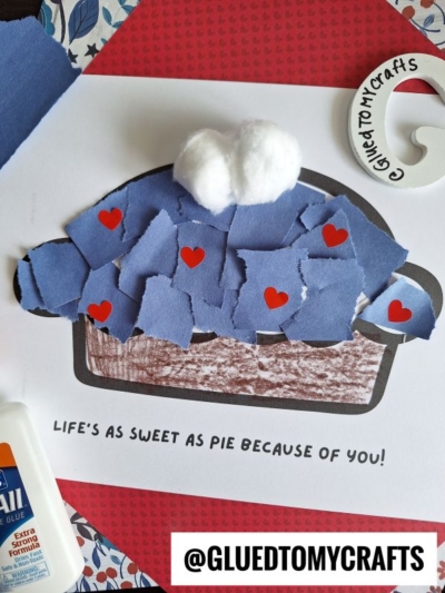 A charming torn paper pie craft features a blue paper crust, red paper hearts, cotton ball whipped cream, and the message “Life’s as sweet as pie because of you!” on a red background. @GLUEDTOMYCRAFTS appears at the bottom.