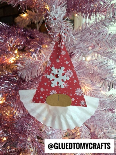 A handmade gnome Christmas ornament—perfect for coffee filter crafts for kids—features a red, snowflake-patterned hat, oval nose, and white coffee filter beard, hanging on a pink Christmas tree. @GLUEDTOMYCRAFTS text is at the bottom.