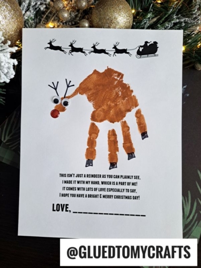 A child’s brown handprint creates a reindeer with googly eyes and a red nose on white paper. Above, Santa’s sleigh silhouette soars. Below is a Holiday Poems From Glued To My Crafts section with space for a signature.