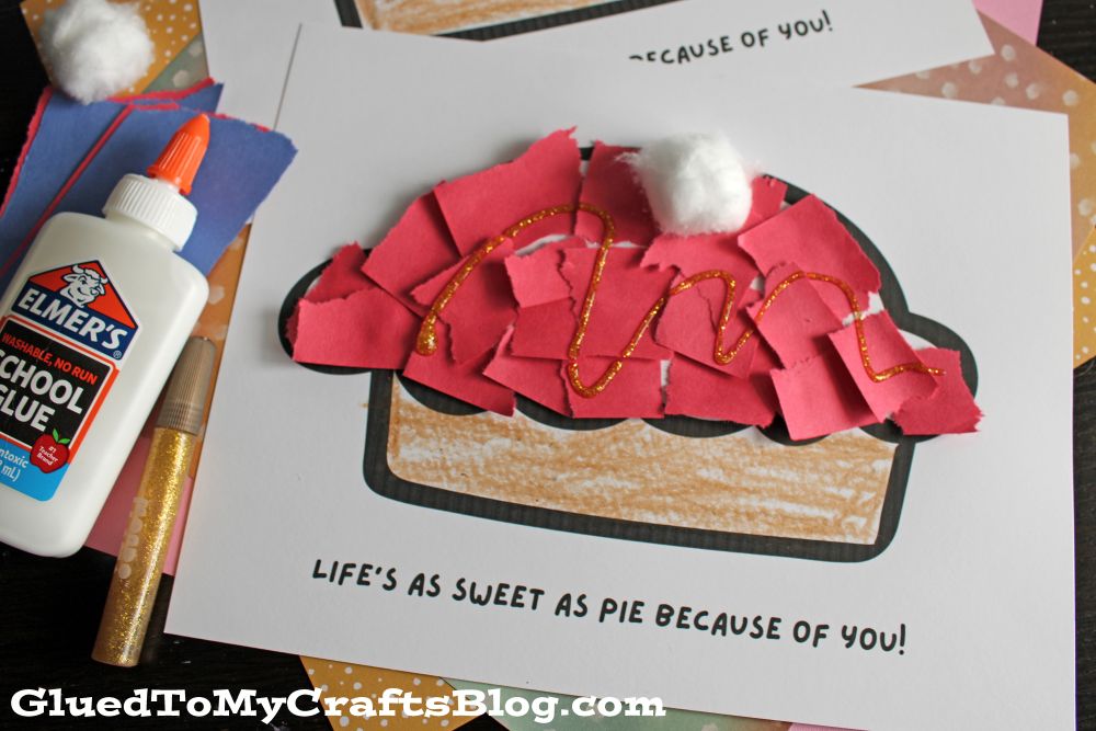 A childrens craft project featuring a paper pie with torn red paper pieces, gold glitter glue, and cotton ball whipped cream on a printable with the phrase Lifes as sweet as pie because of you! Nearby are glue, glitter, and papers.