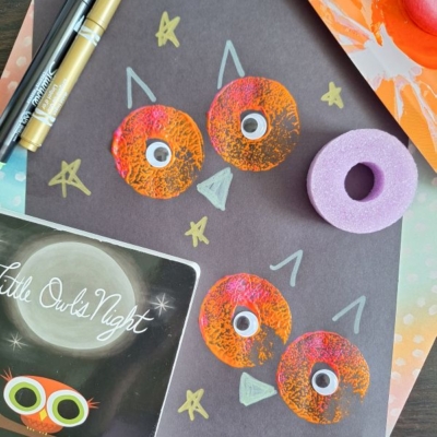 A childrens owl craft made with orange painted circles and googly eyes on black paper, surrounded by markers, a stamp tool, a book titled Little Owls Night, and the text @GLUEDTOMYCRAFTS.