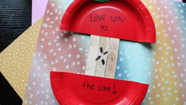 A craft made from red paper plates forms a sliced apple, with “Love you to the core!” written inside. The background includes colorful, polka-dot papers. GluedToMyCraftsBlog.com appears at the bottom.