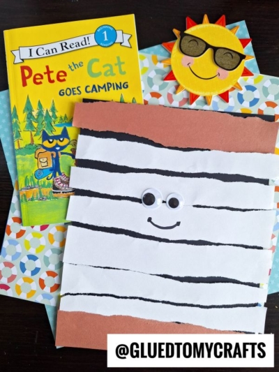 Children’s book “Pete the Cat Goes Camping,” a paper craft with wiggly eyes and stripes resembling a s’more, a smiling sun craft, and colorful patterned papers. Text: @GLUEDTOMYCRAFTS.