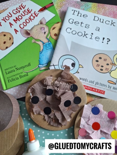 Children’s books “If You Give a Mouse a Cookie” and “The Duckling Gets a Cookie!?” with craft supplies nearby, including paper cookies decorated with brown and black circles, glue, and a @gluedtomycrafts label.
