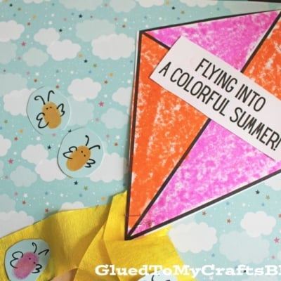A colorful paper kite with FLYING INTO A COLORFUL SUMMER! written on it is placed on a sky-themed background with clouds and bees. The kite has a yellow ribbon tail with hearts.