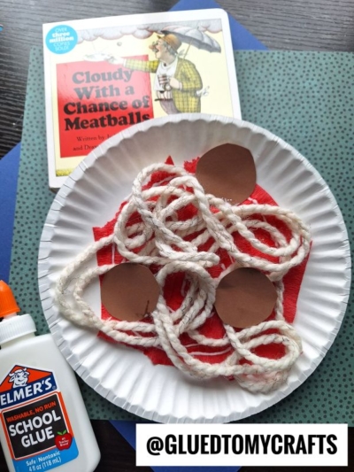 A fun summer craft idea inspired by Cloudy With a Chance of Meatballs uses a paper plate with red tissue for sauce, white yarn for spaghetti, and brown paper circles for meatballs. Elmer's glue and the book complete this creative activity.