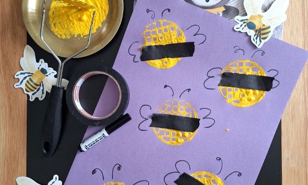 A childrens craft setup shows a book titled The Little Bee, yellow paint, a potato masher, black tape, and a sheet with bee and honeycomb art, surrounded by cut-out bees. @GLUEDTOMYCRAFTS is displayed at the bottom.