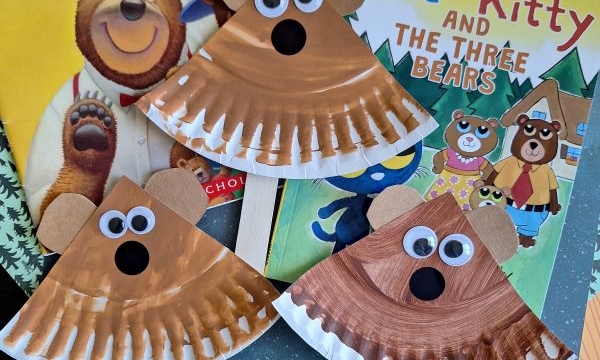 Three bear crafts made from paper plates, googly eyes, and craft sticks are displayed on top of the books Goldilocks and the Three Bears and Pete the Kitty and the Three Bears. A @GLUEDTOMYCRAFTS watermark is shown.