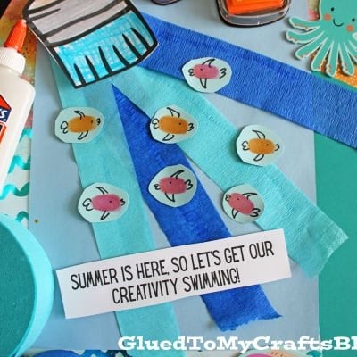 A selection of craft supplies, including Elmers glue, construction paper, paper fish cutouts, ink pads, an octopus shape, blue crepe paper, and a sign that says Summer is here—perfect for creativity on our Summer Printables - Landing Page!.