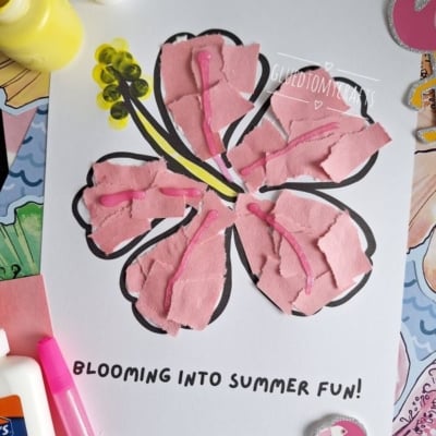 A craft project of a hibiscus flower made with torn pink paper pieces glued onto a printed outline, with yellow and black details. Supplies like glue, yellow paint, and a brush are nearby. Text reads “BLOOMING INTO SUMMER FUN!.