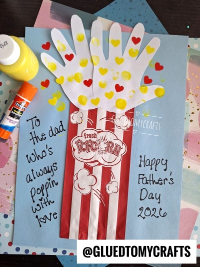 A handmade HANDPRINT FATHER'S DAY card features red and white popcorn bag art with handprint cutouts as popcorn, decorated with yellow and red hearts. Text reads: To the dad who's always poppin with love. Happy Fathers Day 2026.