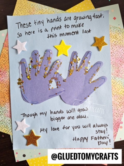 Handprint Father’s Day card featuring two purple paper handprints decorated with gold star confetti and foam stars, set on blue paper with a handwritten poem and @GLUEDTOMYCRAFTS at the bottom. A perfect HANDPRINT FATHER'S DAY keepsake!.