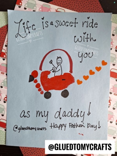 A handmade HANDPRINT FATHER'S DAY card features a red car crafted from a handprint, with a stick figure driving and orange hearts trailing behind. The text reads, Life is a sweet ride with you as my daddy! Happy Fathers Day!.