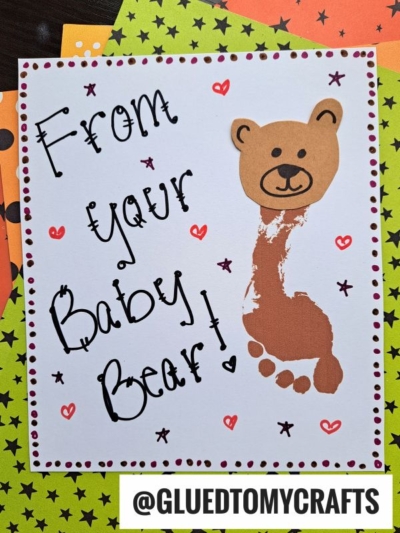 A handmade HANDPRINT FATHER'S DAY card with From your Baby Bear! in playful black text, featuring a bear made from a brown footprint for the body and a cute bear face above. The card is bordered by star-patterned paper.