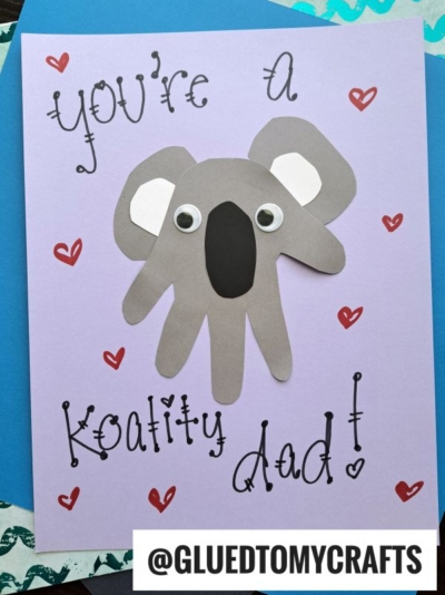 A handmade HANDPRINT FATHER'S DAY card features a koala crafted from cut-out paper handprints with googly eyes. The card reads You’re a Koality Dad! with red heart accents and @GLUEDTOMYCRAFTS at the bottom.