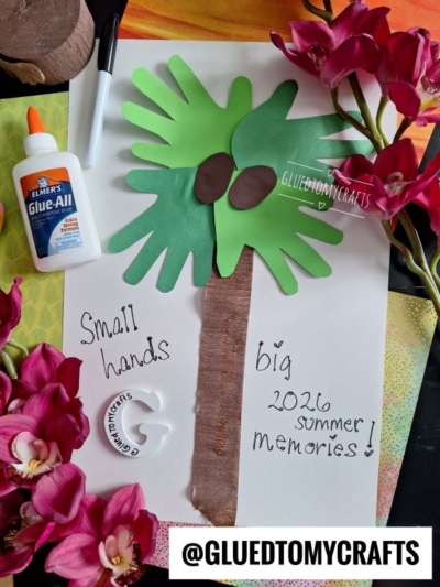 A palm tree craft made with green handprints for leaves and brown paper for the trunk is surrounded by pink flowers, a bottle of glue, and a marker. Text reads, “Small hands big 2026 summer memories!”.