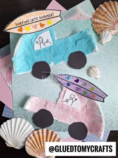 Two paper plate beach cars, crafted from colored paper and tissue, each with a drawing of a person and a surfboard on the roof, are displayed on layered pastel paper with seashells. Text reads SURFING INTO SUMMER! and @GLUEDTOMYCRAFTS.