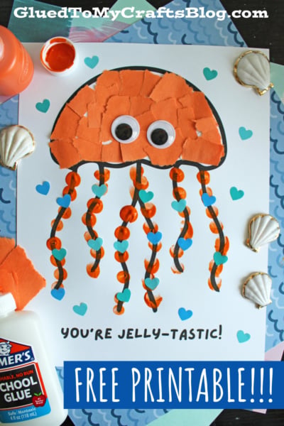 A colorful jellyfish craft made of orange paper pieces, googly eyes, and striped tentacles is on a white sheet with blue hearts. YOURE JELLY-TASTIC! is written below. Seashells, glue, and paint are nearby. “FREE PRINTABLE!!!” is displayed.