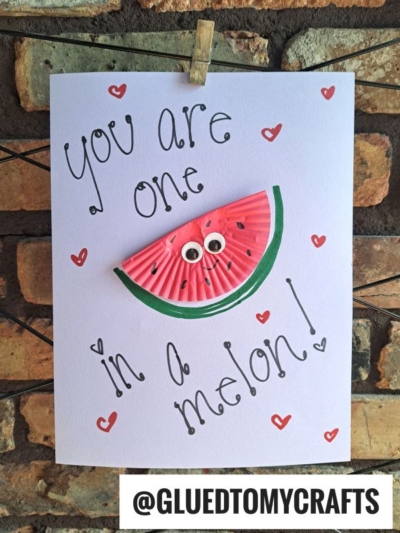 A handmade cupcake liner card crafts a watermelon slice with googly eyes, surrounded by small red hearts. It reads "You are one in a melon!" with the username @GLUEDTOMYCRAFTS at the bottom.