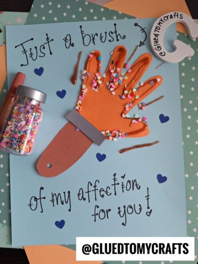 A handmade HANDPRINT FATHER'S DAY card features a paper hand as a paintbrush, decorated with colorful sprinkles, glitter, and hearts. The card reads “Just a brush of my affection for you!” and shows the @GLUEDTOMYCRAFTS handle.