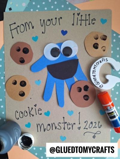A handmade HANDPRINT FATHER'S DAY craft card with a blue handprint monster, googly eyes, paper cookies, and "From your little cookie monster! 2026." Art supplies and heart shapes surround the card. @GLUETOMYCRAFTS is at the bottom.