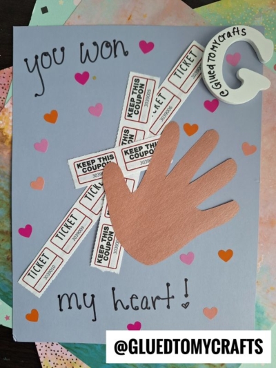 Handmade HANDPRINT FATHER'S DAY card featuring a brown hand cutout, "Keep This Coupon" tickets, colorful heart stickers, and handwritten text: “You won my heart!” with a white letter G in the corner.
