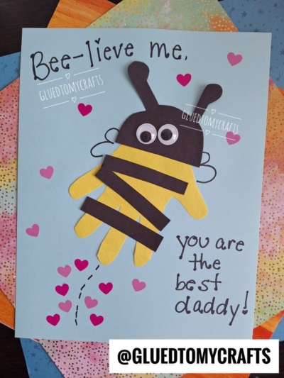 A HANDPRINT FATHER'S DAY card features a bee made from a yellow handprint with black stripes, wings, googly eyes, and antennae. The text reads, Bee-lieve me, you are the best daddy! with pink hearts scattered around.