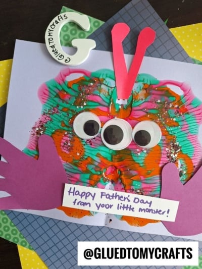 A colorful HANDPRINT FATHER'S DAY card features a painted butterfly-like monster with googly eyes, purple paper arms, red antennae, and a note saying, Happy Fathers Day from your little monster! @GLUEDTOMYCRAFTS is displayed at the bottom.